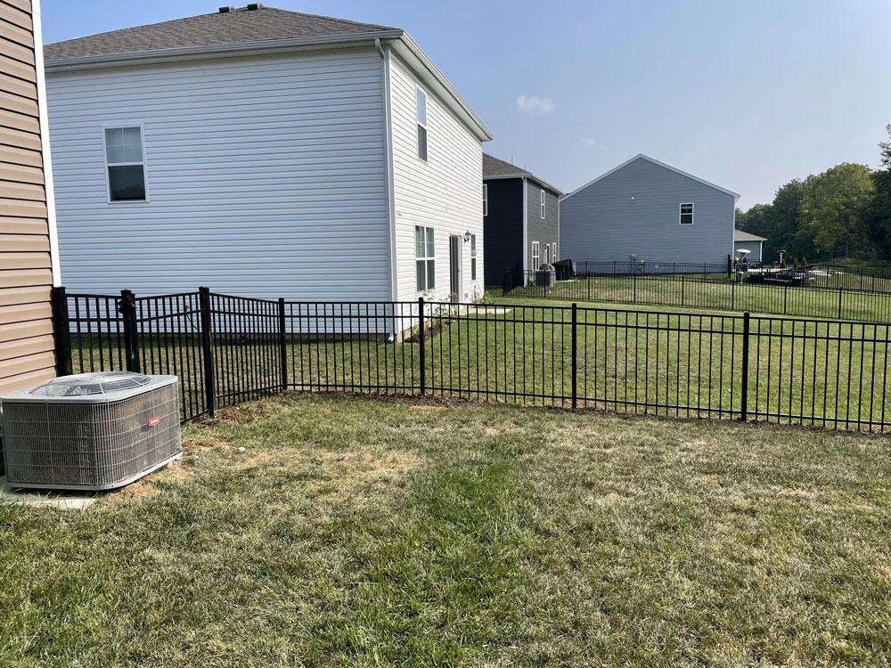 Black aluminum fences close off the backyards of two different houses.