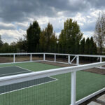 A custom wire tennis court fence with a single gate on one side.