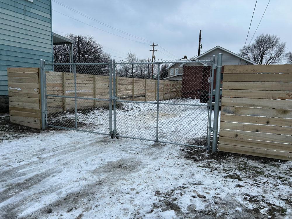 A commercial wood fence with chain link gate on wheels.