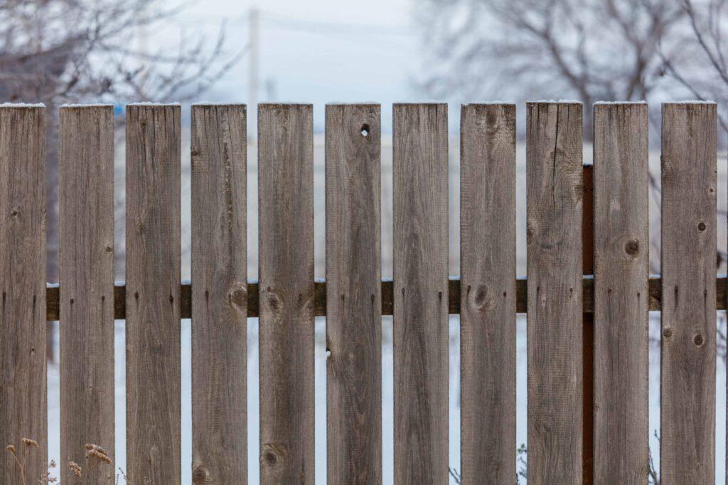 A wooden fence with a snowy background