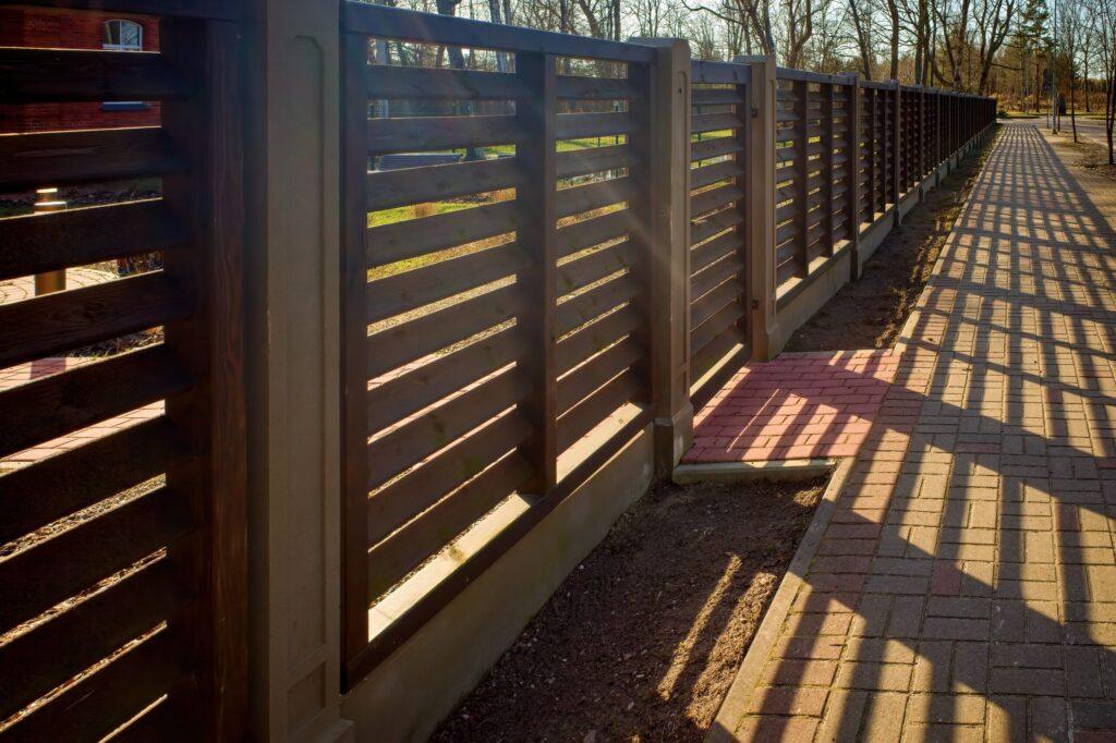 Long wooden fence. Fencing of private territory. Fence along the sidewalk.