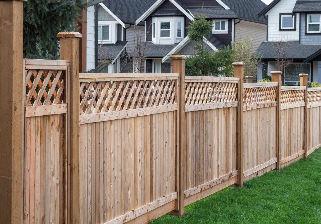 Nice new wooden fence around house. Wooden fence with green lawn.