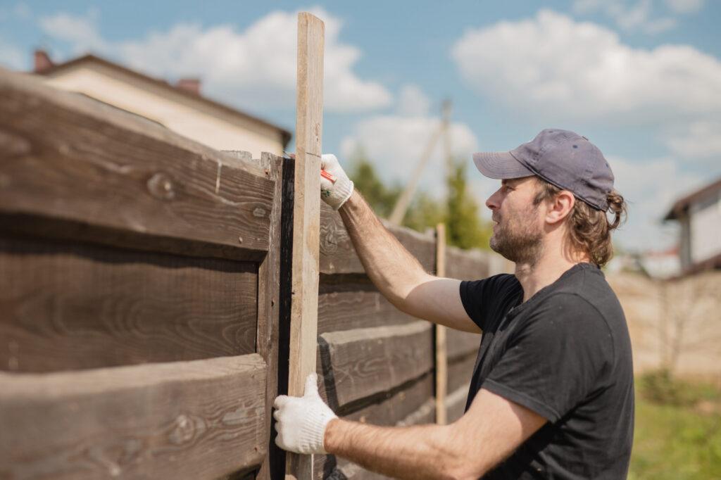 Man builds sections of fence around his yard out of planks