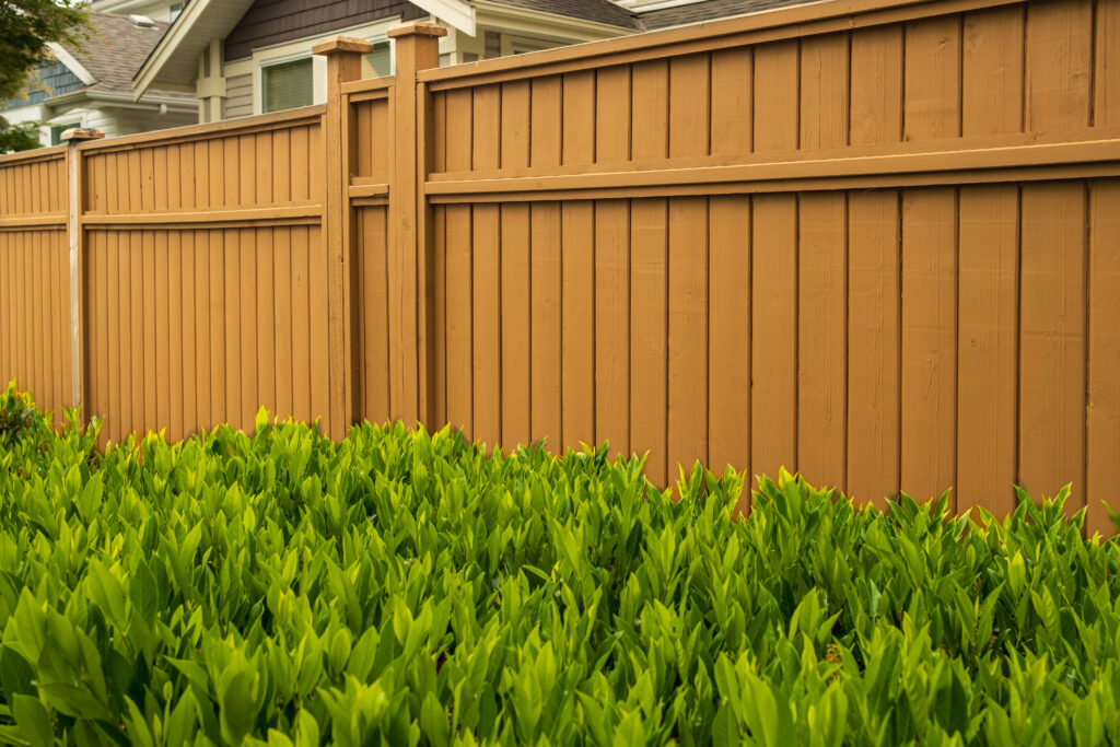 Nice wooden fence around house. Wooden fence with green lawn. Street photo