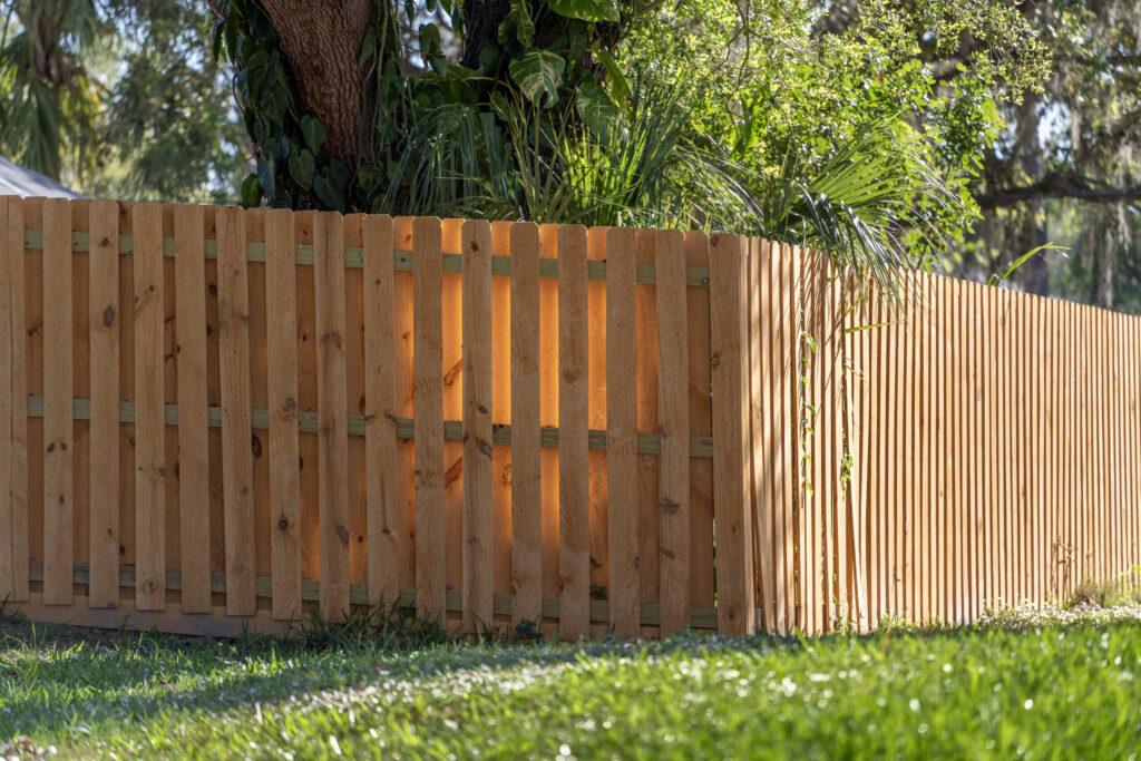 Wooden picket fence on green lawn surrounding property grounds for backyard protection and privacy