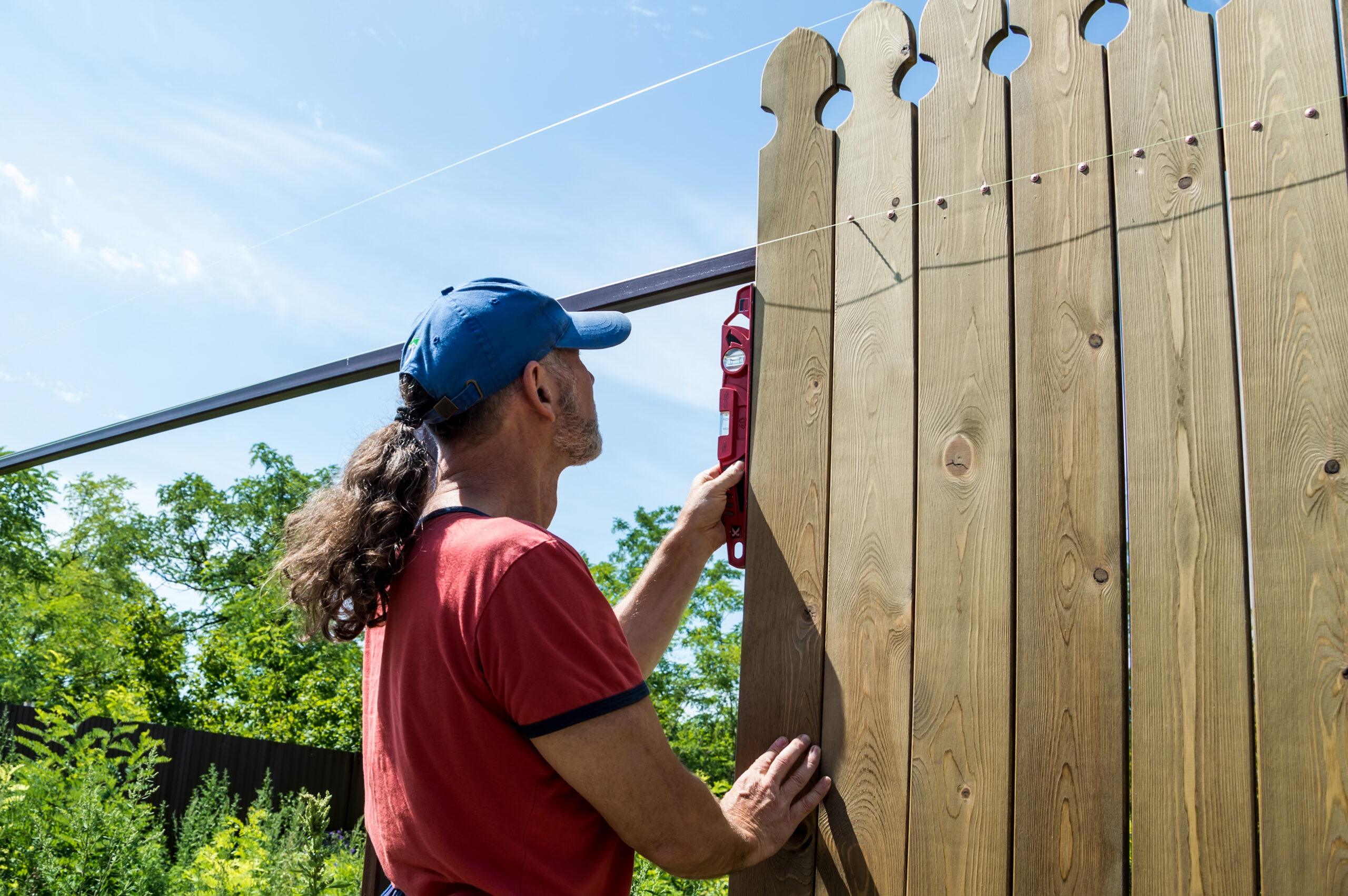 A Man Builds A Wooden Fence