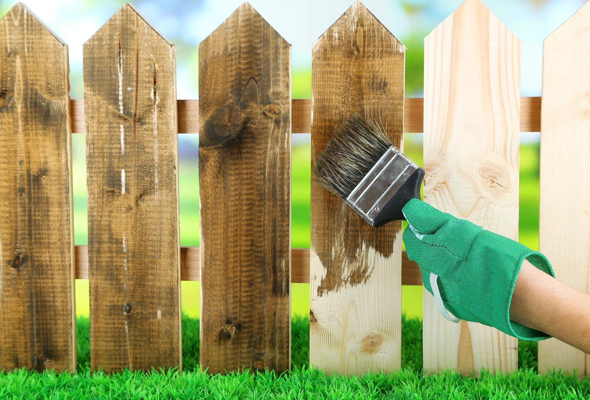 Applying Protective Varnish To Wooden Fence On Bri