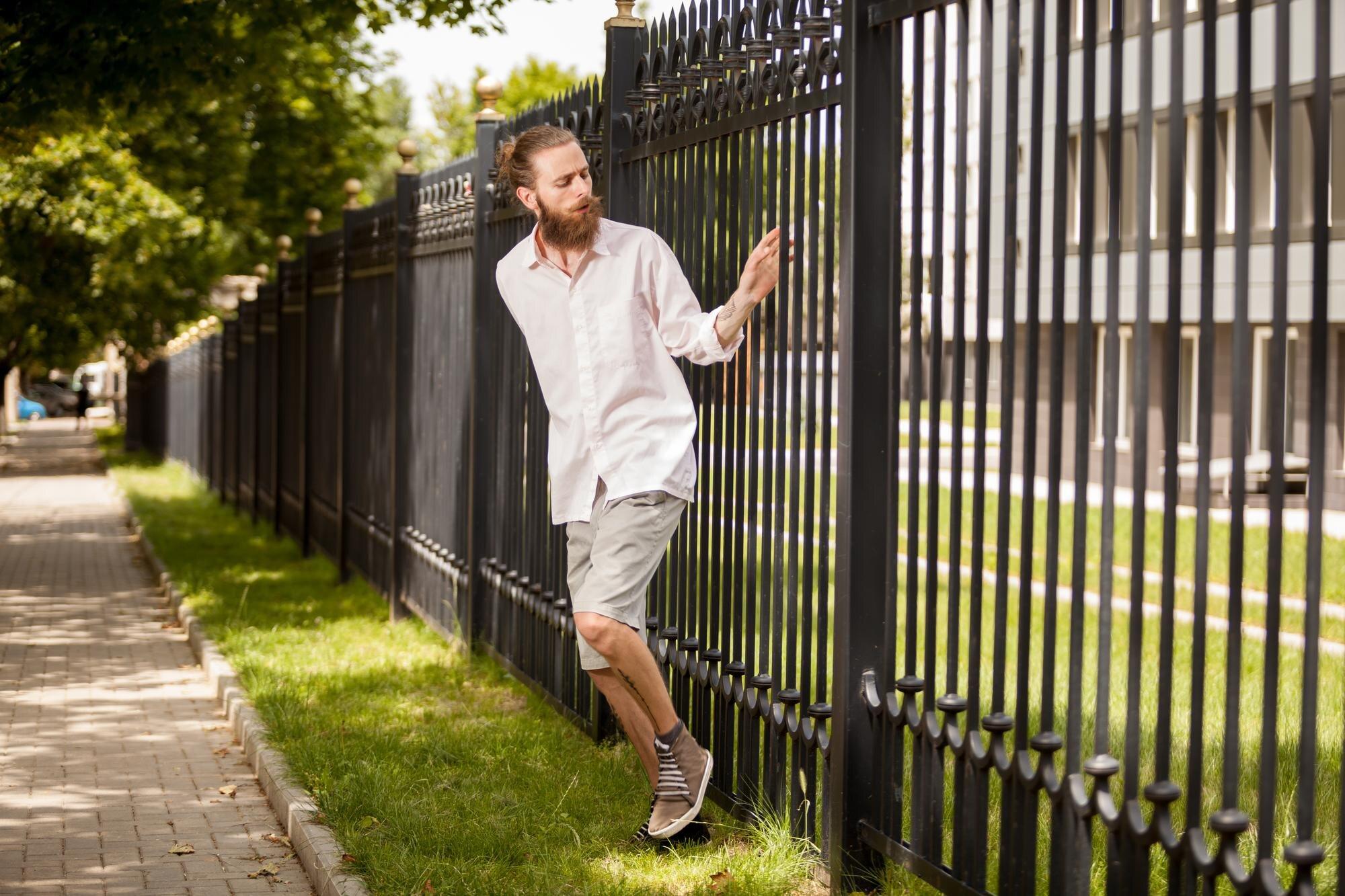 Bearded Hipster Posing Next To A Fence