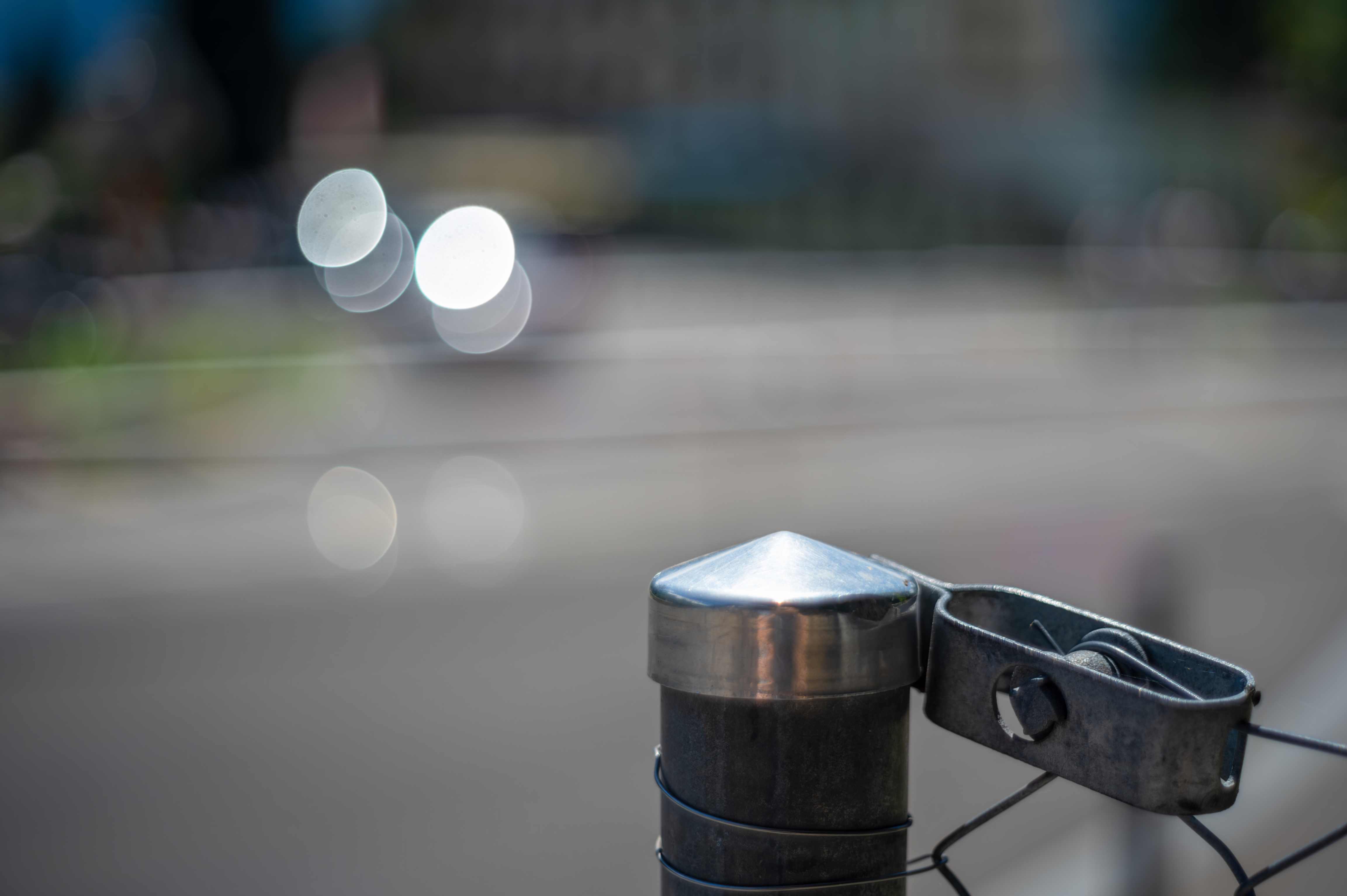 Close Up Of Metallic Fence Post With Bokeh Backgro