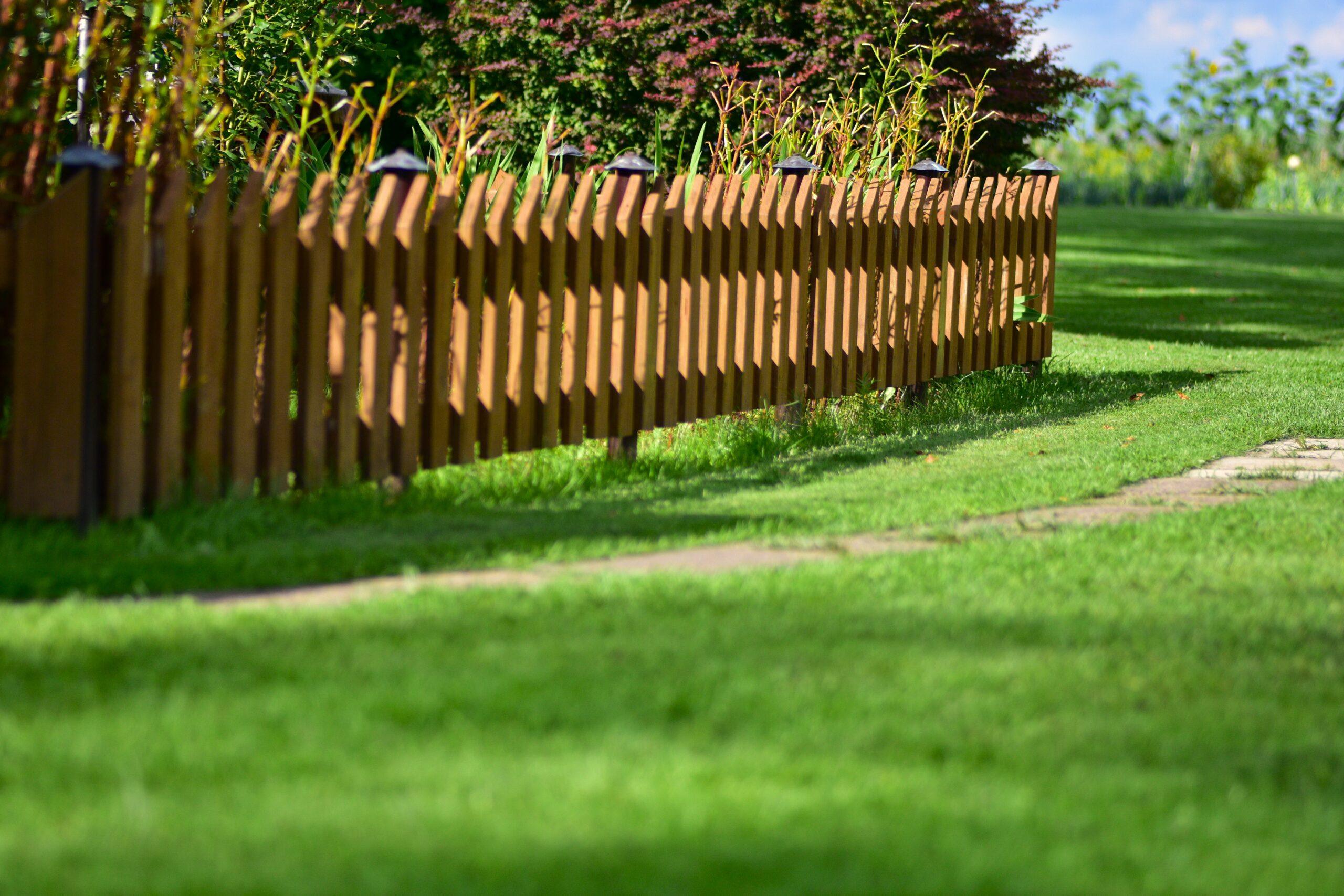 Long Wooden Fence Line With Garden Plants And Brig