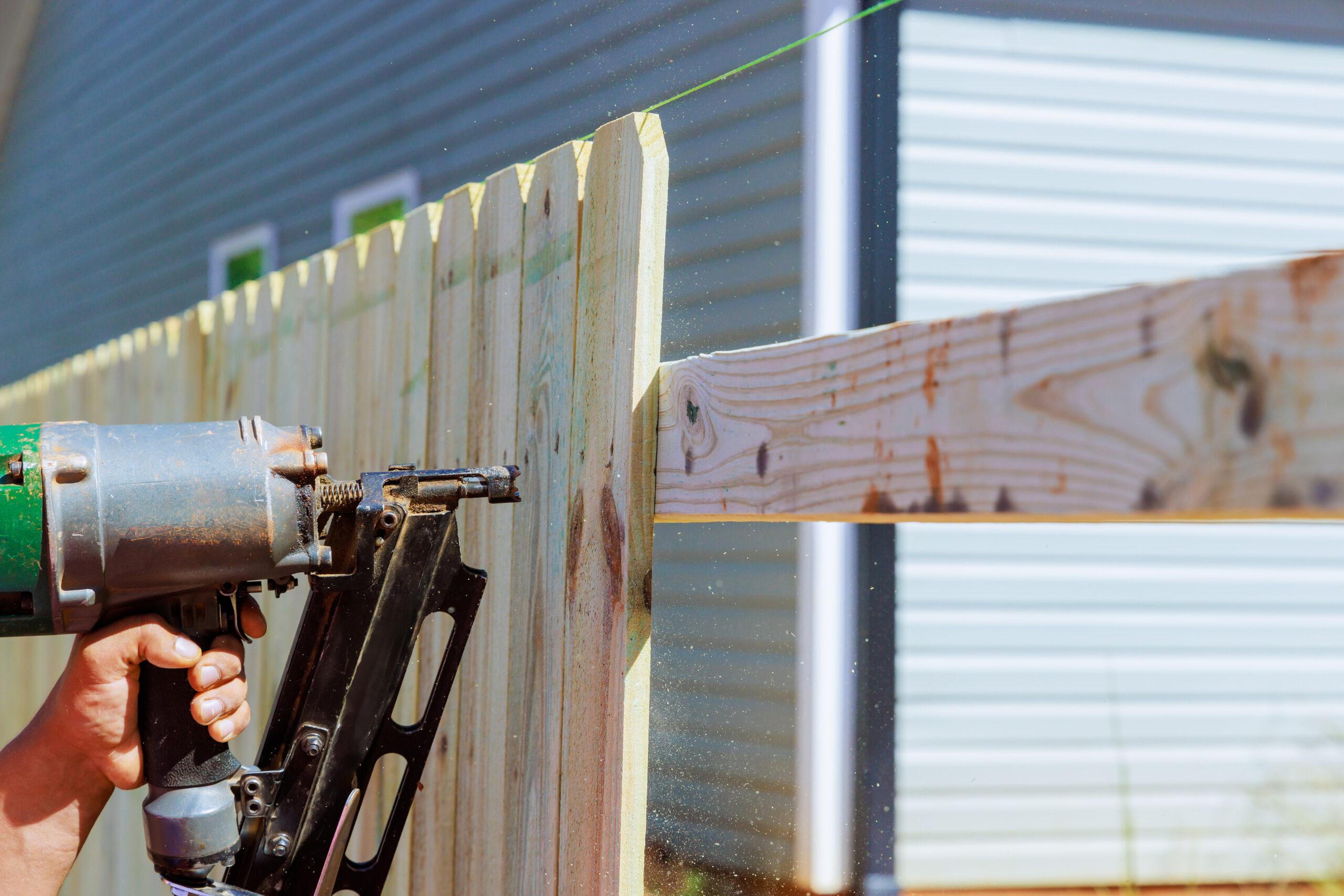 Man Builds Sections Of Nailing A Wooden Fence Arou