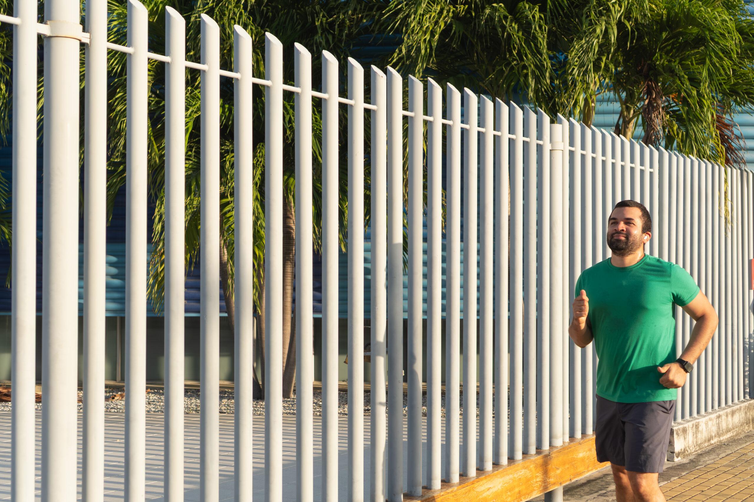 Man Jogging Near White Fence In The City