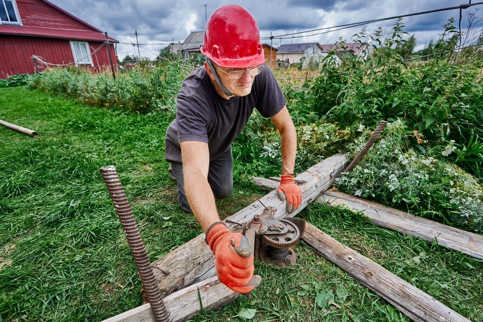 Seasonal Worker Uses Winch In Garden Plot In Summe