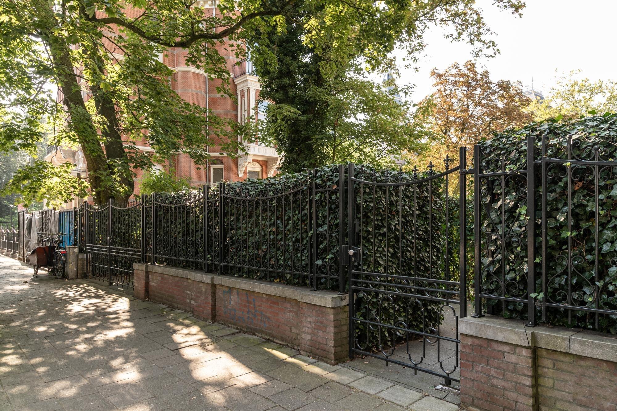 The Fence Is Closed By A Brick Wall And Bushes