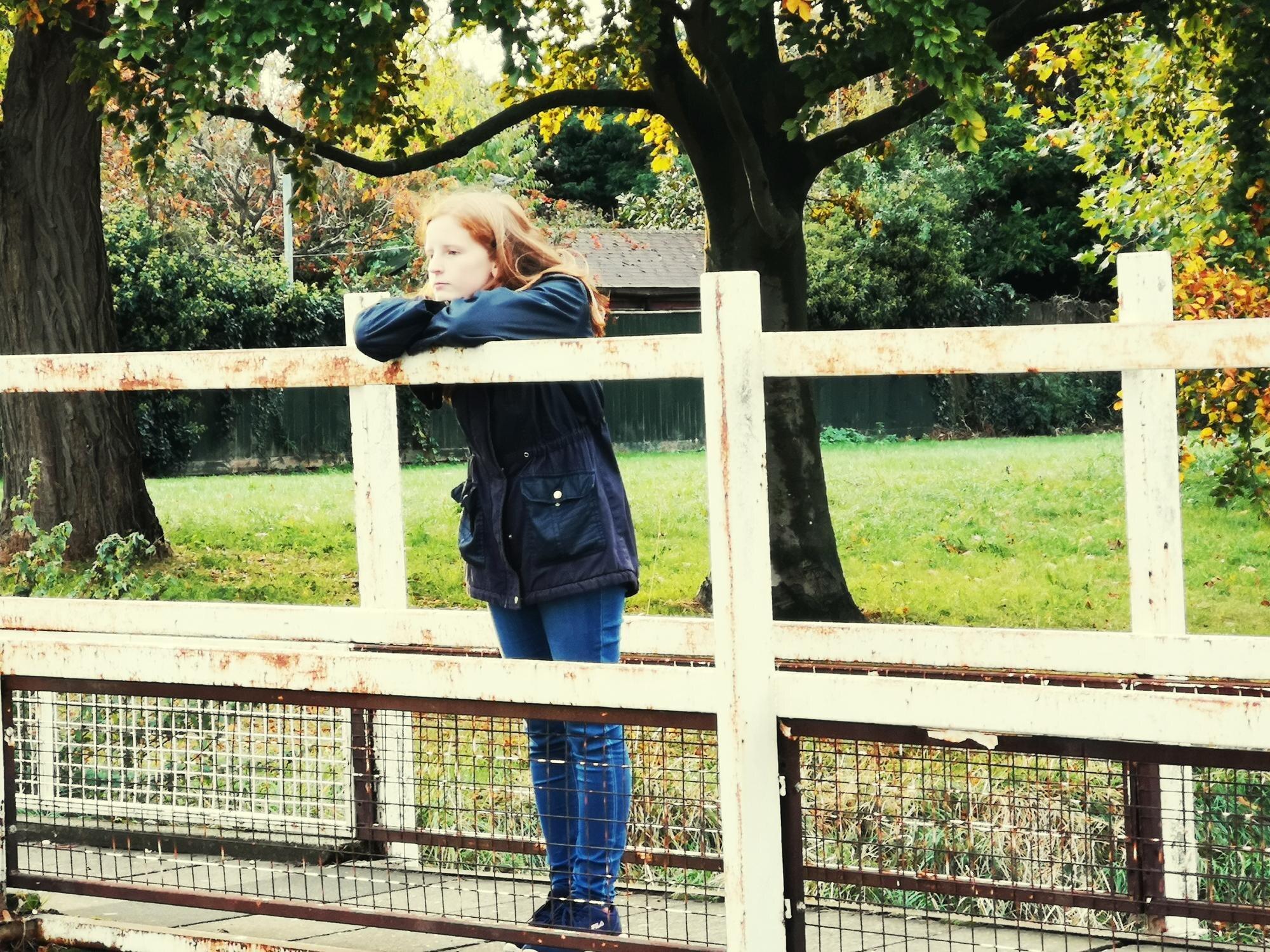 Woman Standing By Railing Against Trees